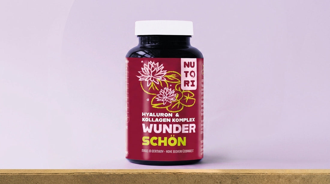Eine braune Glasflasche der Nutori Wunderschön Kapseln neben einem Glas frischem Wasser und natürlichen Inhaltsstoffen wie Hagebutten auf einem hellen, sauberen Hintergrund.
