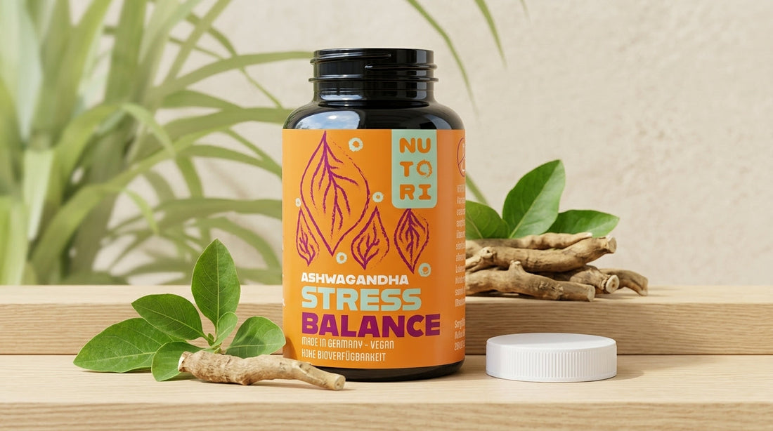 Eine braune Braunglasdose Nutori Stress Balance Kapseln umgeben von getrockneten Ashwagandha-Wurzeln und zarten gelben Blüten der Rhodiola Rosea auf einem hellen Holzgrund.